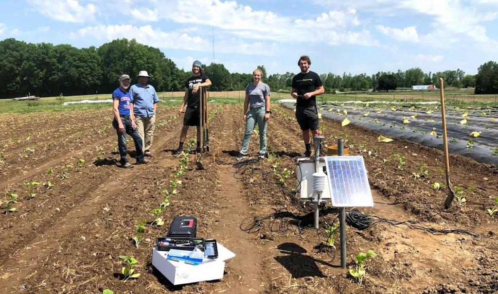 Biosystems engineering team stands next to the solar well project at the Student Organic Farm